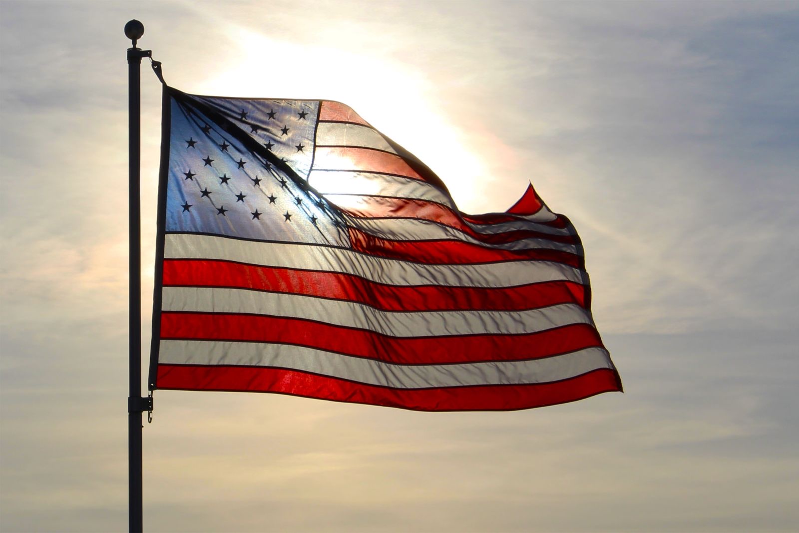 An American flag waving against a glowing sunset sky